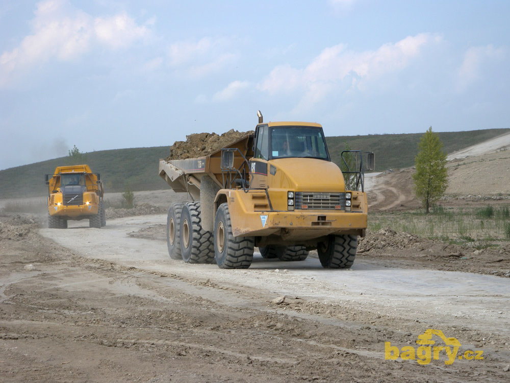 Kloubový dempr Caterpillar 735, za ním Volvo A35E
