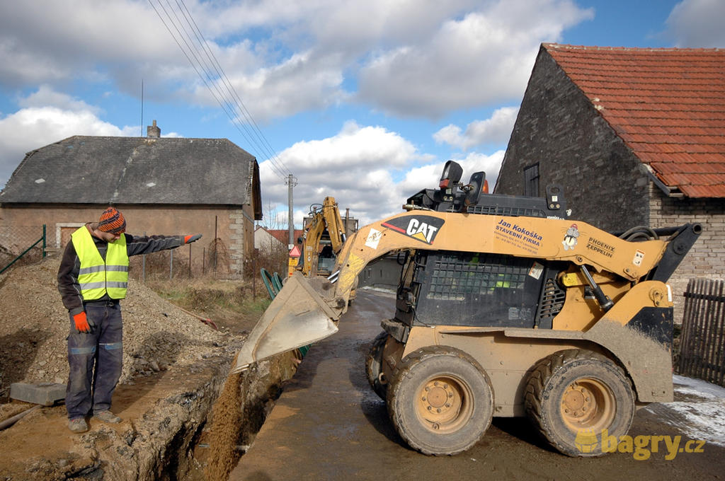 Kolový nakladač Caterpillar 246B zasypává výkop