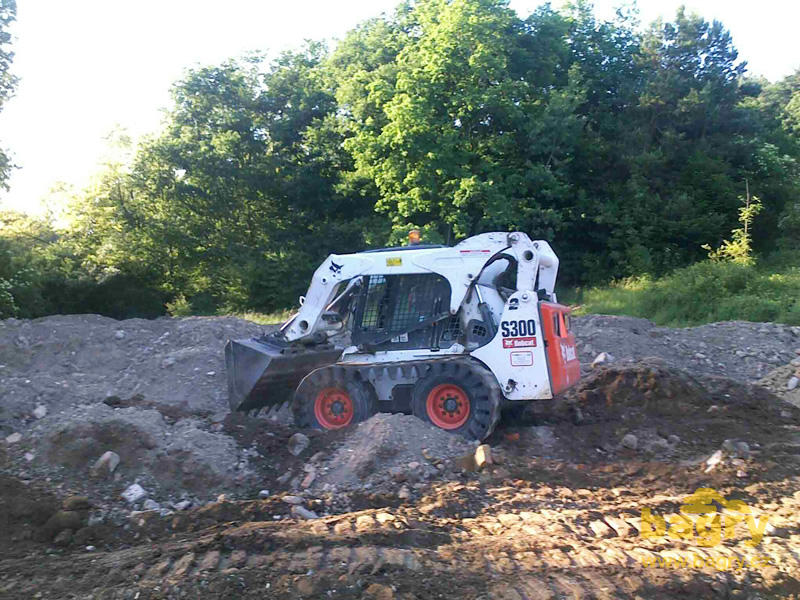 Bobcat S300 s pásy Solideal OTT při rozhrnování skládky zeminy v Modré