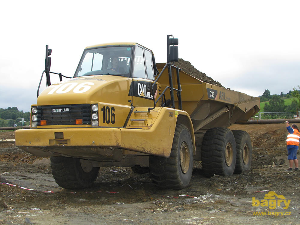 Kloubový dempr Caterpillar 735 při nájezdu před složením materiálu